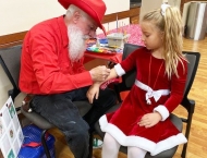 girl in red velvet dress getting arm painted at Dobson Ranch 2019 Breakfast with Santa event