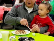 father and baby eating pancakes at Dobson Ranch 2019 Breakfast with Santa event
