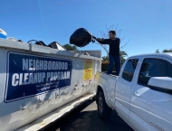 resident tossing garbage into large dumpster at Dobson Ranch 2020 Spring Community Clean Up event